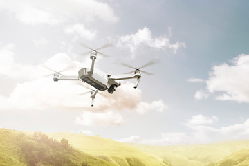 Fototapeta na wymiar White drone with camera flying above green hills