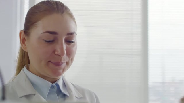 Tilt up shot of cheerful female optometrist smiling and giving instructions to unrecognizable patient during eye exam