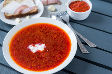plate of borscht with sour cream, pieces of lard, not a wooden background