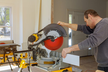 finishing work the worker cuts the wood moldings baseboard on the miter saw