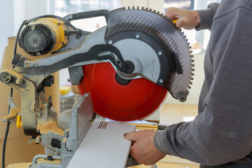 Carpenter working using circular saw rotating saw cutting wood baseboard