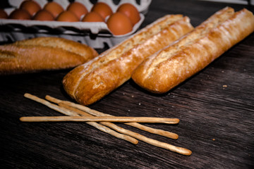 Loaves of bread, grisinni bread sticks an dozen of eggs. Copy space.