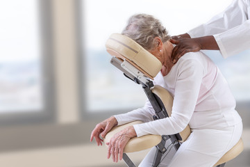 Senior woman getting massage in chair in therapy room