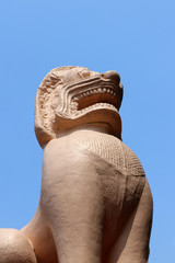 Ancient stucco lion statue and blue sky background.