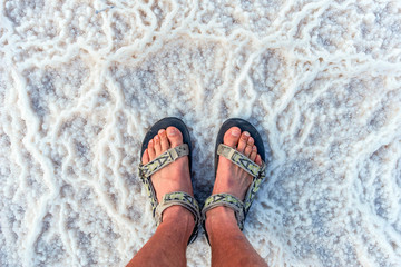 young man in the sandals stands on incredibly fantastic and unique natural patterns from the salt...