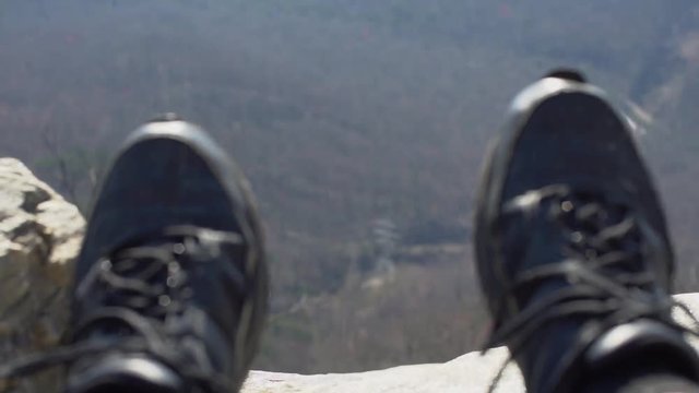 A person dangles their feet over a cliff at pretty place chapel.