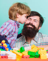 Fathers day. Father and son have fun with bricks. Bearded hipster and boy play together. Dad and child build of plastic blocks. Child care concept. Happy family. Child development and upbringing