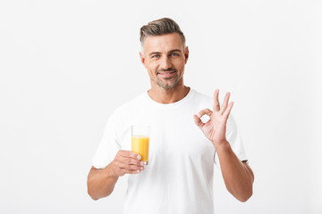 Image of attractive man 30s with bristle wearing casual t-shirt showing ok sign while holding glass...