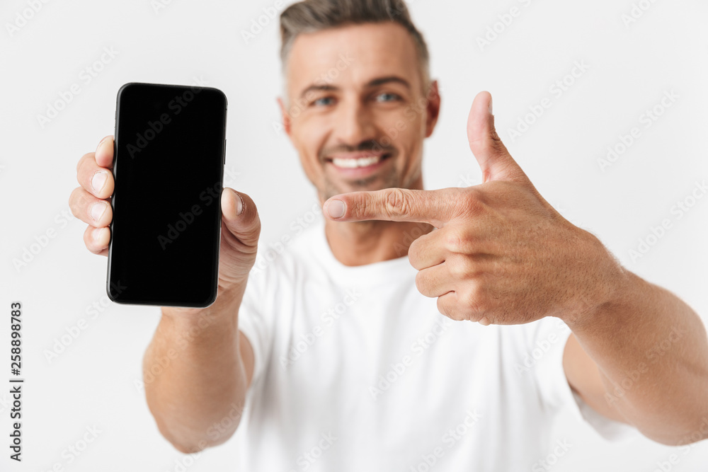 Sticker image of successful man 30s wearing casual t-shirt holding and demonstrating cell phone