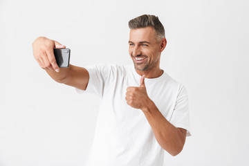 Successful man 30s wearing casual t-shirt looking on camera while taking selfie photo