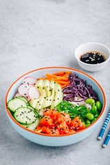 Salmon poke bowl with rice, avocado, seaweed, carrots, cucumber, radishes and edamame beans