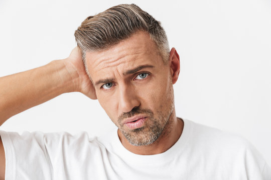 Image of caucasian man 30s with bristle wearing casual t-shirt grabbing head due to pain