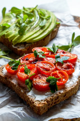 Healthy vegan breakfast concept. Vegetarian cheese spread sandwich, ripe avocado slices, sun dried tomato, toasted bread. clean eating. White table background. Top view, close up, copy space, flat lay