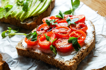 Healthy vegan breakfast concept. Vegetarian cheese spread sandwich, ripe avocado slices, sun dried tomato, toasted bread. clean eating. White table background. Top view, close up, copy space, flat lay