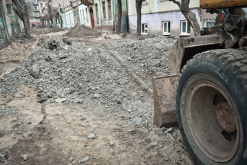 Fototapeta na wymiar The street of the city is torn down. Construction and laying of pipelines and sewerage. Large excavator in construction. Chernivtsi, Ukraine, Europe, March 2019.