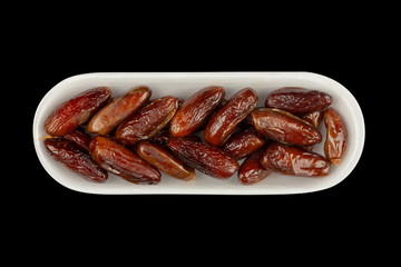 dried dates in white styrofoam packaging isolated on black background close-up, top view