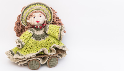 knitted doll in a loose dress and with beads on a white background