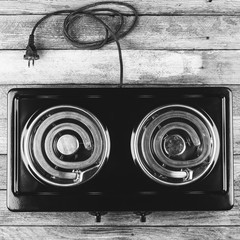 electric stove with two electric forks on a wooden table, top view close-up, black and white photo