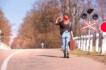 Beautiful traveling woman with retro suitcase on the road
