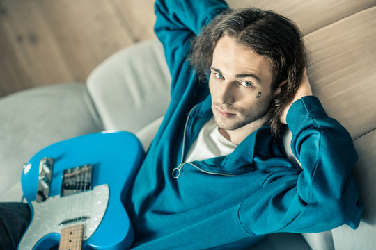 Handsome young man stretching out and having hands behind his head