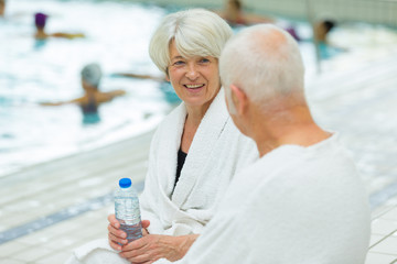 senior couple sat talking poolside