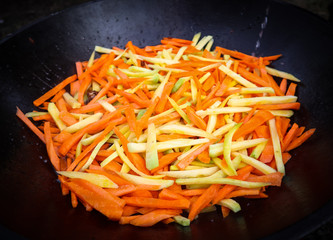 Yellow and orange carrot in cauldron. Pilaf cooking process.