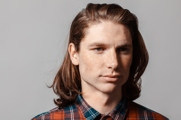 Portrait of a man with long hair and freckles, dressed in a checkered shirt
