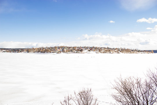 Village across the river. Real Russian Winter. Winter Landscape in river. Country house on lake shore in winter