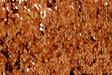 Glittering sequin texture in orange tone.