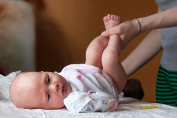 The newborn lies on his back while his mother changes his diaper