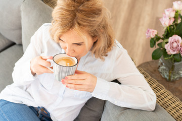 Attraktive ältere Frau genießt zuhause eine Tasse Kaffee 