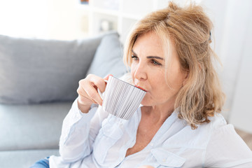 Attraktive ältere Frau genießt zuhause eine Tasse Kaffee 
