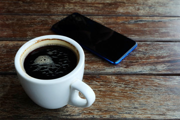 Flat lay photo of smartphone and black coffee on wood table with space for write wording, innovation that change the world such as communication way, business strategies, marketing strategies