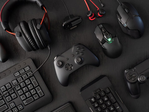 gamer work space concept, top view a gaming gear, mouse, keyboard, joystick, headset, mobile joystick, in ear headphone and mouse pad on black table background.