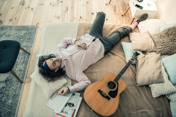 Peaceful good-looking young man lying across king-size bed