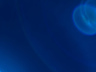 Lens flare effect. Soft defocused blurred light shine on dark blue background