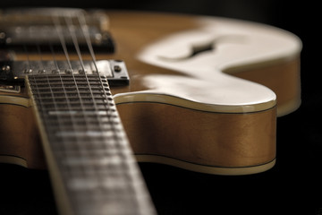 Vintage archtop guitar in natural maple close-up high angle view on black background, frets and veins of maple wood detail in selective focus