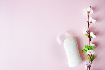 antiperspirant or deodorant with white flowers on pink pastel background . copy space. place for text