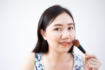 Portrait of Beautiful Asian woman brushing her beauty face close up on white background.  Easy beauty at home concept.