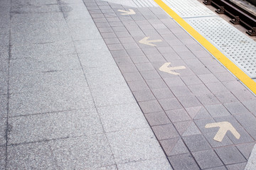 Fototapeta premium Photograph of rail station platform with an entrance and exit arrow sign on the floor.