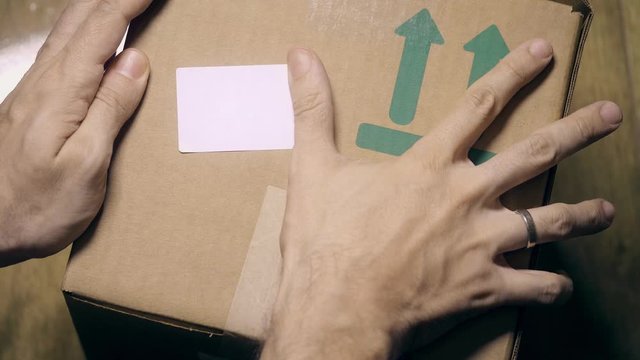 Man sticks a white sticker label to parcel carton box. Place for revealing text or logo