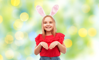 Obraz na płótnie Canvas easter, holidays and childhood concept - happy girl wearing bunny ears headband over green lights background