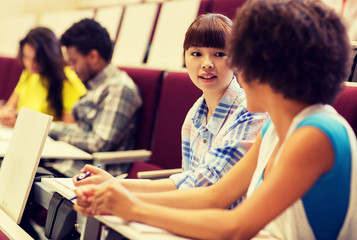 education, high school, university, learning and people concept - group of international students talking in lecture hall