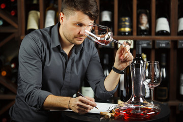 Sommelier looking at red wine glass with beverage