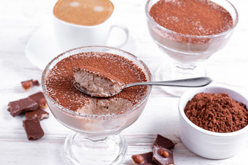 Glass with delicious banana pudding and cocoa on table