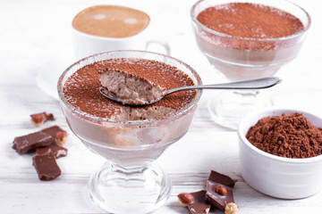 Glass with delicious banana pudding and cocoa on table