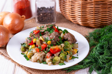 Chicken liver with vegetables in a plate on a table