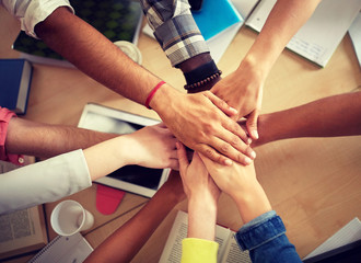 education, school, teamwork and people concept - group of international students with hands on top...