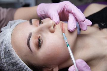 The doctor cosmetologist makes the Rejuvenating facial injections procedure for tightening and smoothing wrinkles on the face skin of a beautiful, young woman in a beauty salon.