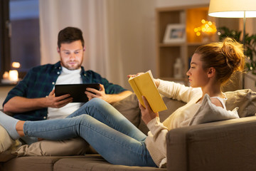 leisure and people concept - couple with tablet computer and book at home in evening